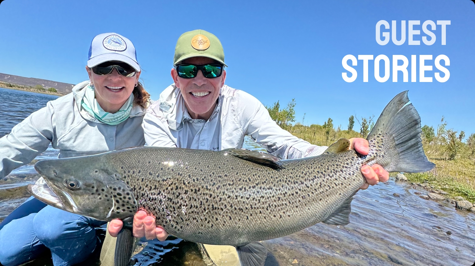 Two anglers smiling with a large brown trout