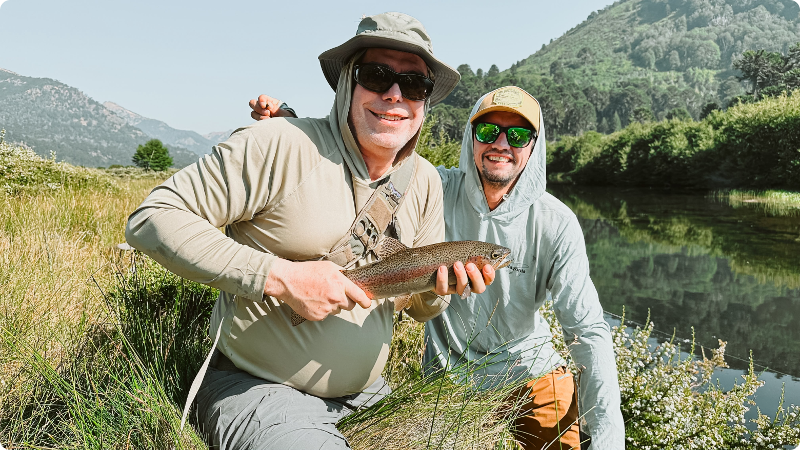 Two guides kneeling in the shallows holding a trout before release