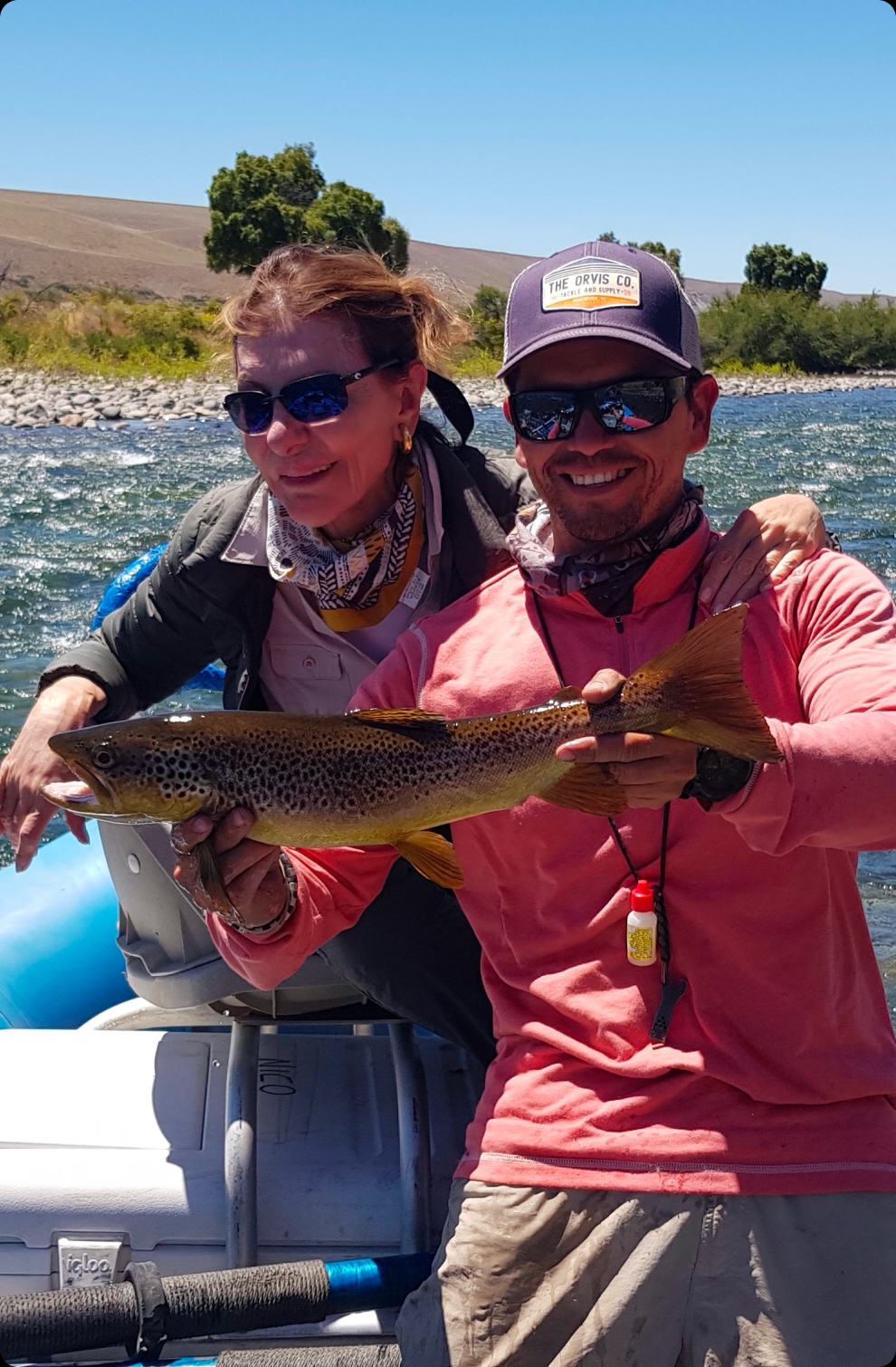 Two anglers with a trout beside the river