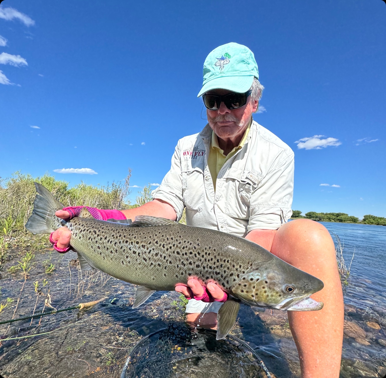 Angler in a cap holding a rainbow trout