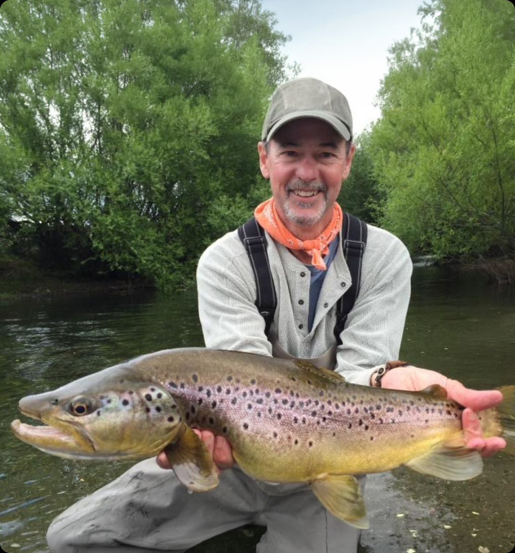 Angler holding a large brown trout by the bank